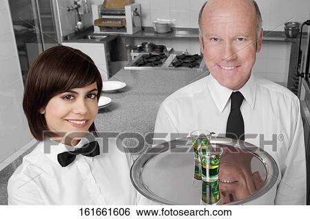 Waiter and a waitress standing in the kitchen and smiling View Large Photo Image Stock Photograph - Waiter and a waitress standing in the kitchen and smiling. Fotosearch