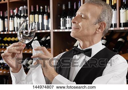 Waiter cleaning a wine glass in a bar View Large Photo Image Stock Photo - Waiter cleaning a wine glass in a bar. Fotosearch