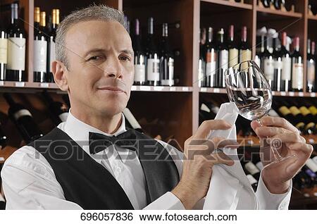 Stock Photograph - Waiter cleaning a wine glass in a bar. Fotosearch