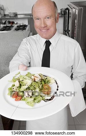 Waiter holding a plate of vegetable salad View Large Photo Image Stock Photo - Waiter holding a plate of vegetable salad. Fotosearch