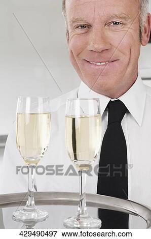Waiter holding a tray of champagne flutes View Large Photo Image Stock Photo - Waiter holding a tray of champagne flutes. Fotosearch