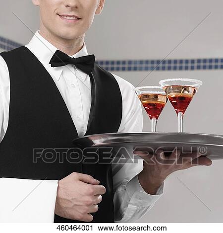 Stock Image - Waiter holding a tray of martini. Fotosearch