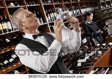 Waiter polishing a wine glass and a businesswoman choosing a bottle in a bar View Large Photo Image Stock Photography - Waiter polishing a wine glass and a businesswoman choosing a bottle in a bar. Fotosearch