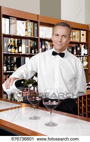 Waiter pouring red wine into wine glasses in a bar View Large Photo Image Stock Image - Waiter pouring red wine into wine glasses in a bar. Fotosearch