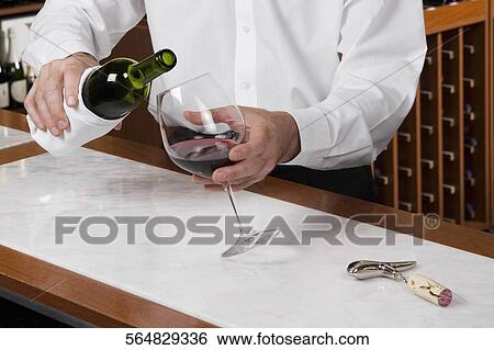 Waiter pouring wine into a glass View Large Photo Image Stock Photograph - Waiter pouring wine into a glass. Fotosearch