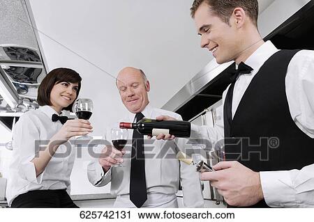 Waiter pouring wine into the glasses of his colleagues View Large Photo Image Stock Image - Waiter pouring wine into the glasses of his colleagues. Fotosearch