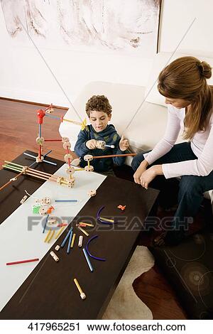 Stock Image - Woman assisting her son in assembling a toy. Fotosearch