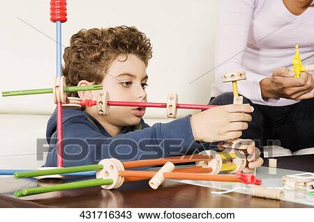 Woman assisting her son in assembling a toy View Large Photo Image Stock Image - Woman assisting her son in assembling a toy. Fotosearch
