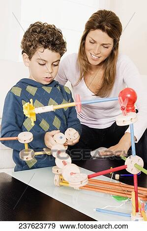 Stock Photo - Woman assisting her son in assembling a toy. Fotosearch