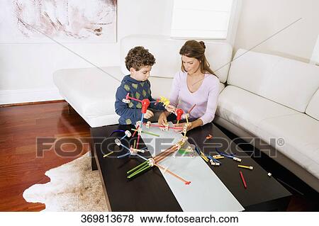 Stock Photo - Woman assisting her son in assembling a toy. Fotosearch