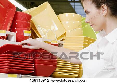 Stock Image - Woman buying crockery in a supermarket. Fotosearch