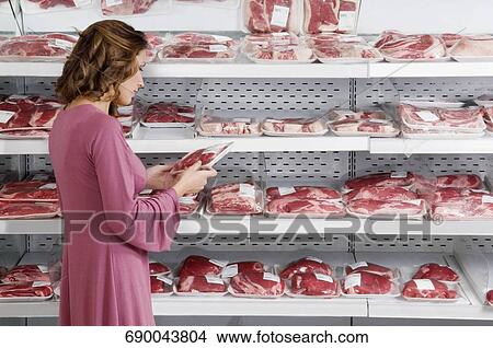 Woman buying meat in a supermarket View Large Photo Image Picture - Woman buying meat in a supermarket. Fotosearch