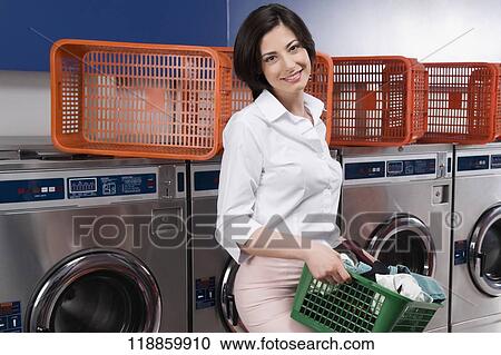 Woman carrying a laundry basket in a laundromat View Large Photo Image Stock Image - Woman carrying a laundry basket in a laundromat. Fotosearch
