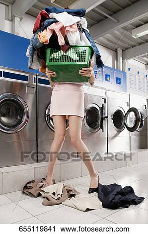 Woman carrying a laundry basket in a laundromat View Large Photo Image Stock Image - Woman carrying a laundry basket in a laundromat. Fotosearch