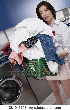 Woman carrying a laundry basket in a laundromat View Large Photo Image Stock Photo - Woman carrying a laundry basket in a laundromat. Fotosearch