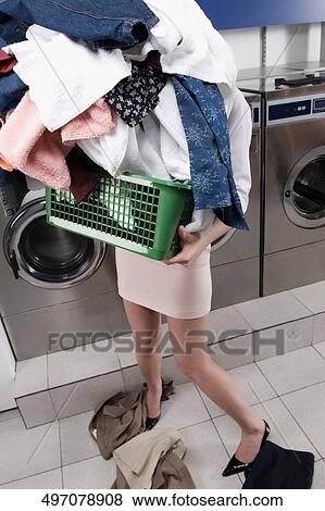 Woman carrying a laundry basket in a laundromat View Large Photo Image Stock Photo - Woman carrying a laundry basket in a laundromat. Fotosearch