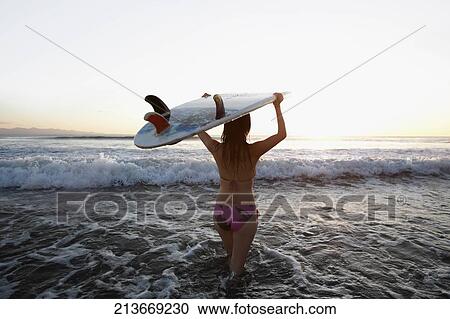 Woman carrying a surfboard on the beach View Large Photo Image Stock Image - Woman carrying a surfboard on the beach. Fotosearch