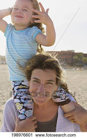 Stock Image - Woman carrying her daughter on her shoulders, Cabo San Lucas, Mexico. Fotosearch