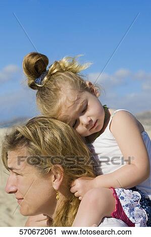 Stock Image - Woman carrying her daughter on her shoulders, Cabo San Lucas, Mexico. Fotosearch