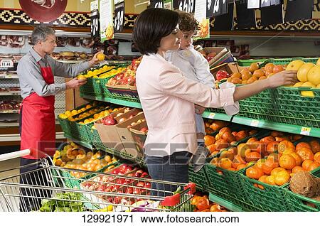Woman carrying her son and buying fruits in a supermarket View Large Photo Image Stock Image - Woman carrying her son and buying fruits in a supermarket. Fotosearch