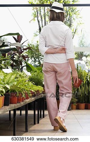 Woman choosing plants in a greenhouse View Large Photo Image Stock Photo - Woman choosing plants in a greenhouse. Fotosearch