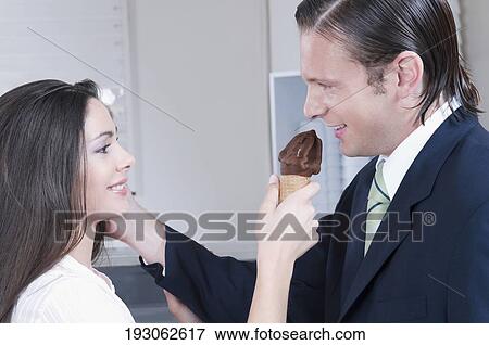 Stock Photo - Woman feeding ice cream to a man. Fotosearch