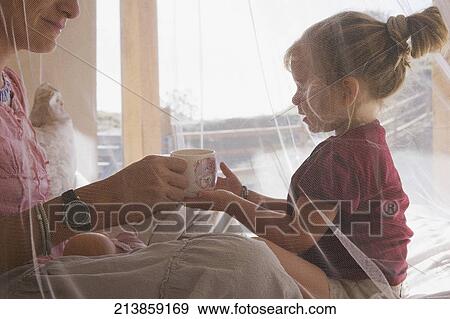 Woman giving a cup of tea to her daughter View Large Photo Image Stock Photo - Woman giving a cup of tea to her daughter. Fotosearch