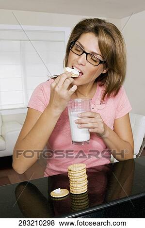 Woman having cookies and milk View Large Photo Image Stock Photo - Woman having cookies and milk. Fotosearch