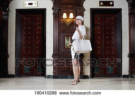 Stock Photo - Woman holding a bag in a hotel lobby, Biltmore Hotel, Coral Gables, Florida, USA. Fotosearch