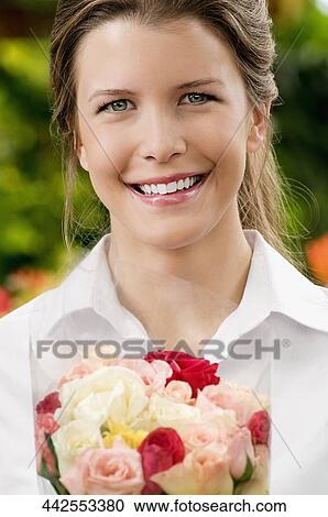 Stock Image - Woman holding a bouquet of flowers and smiling. Fotosearch
