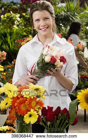 Woman holding a bouquet of flowers and smiling View Large Photo Image Stock Photo - Woman holding a bouquet of flowers and smiling. Fotosearch