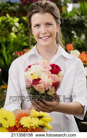 Stock Photograph - Woman holding a bouquet of flowers and smiling. Fotosearch