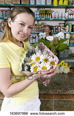 Woman holding a bouquet of flowers in a flower shop View Large Photo Image Stock Photograph - Woman holding a bouquet of flowers in a flower shop. Fotosearch