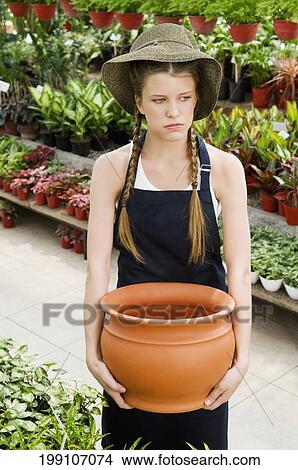Woman holding a pot in a greenhouse View Large Photo Image Picture - Woman holding a pot in a greenhouse. Fotosearch
