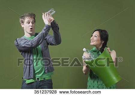 Stock Photo - Woman holding a recycling bin and a man looking into an empty water bottle. Fotosearch