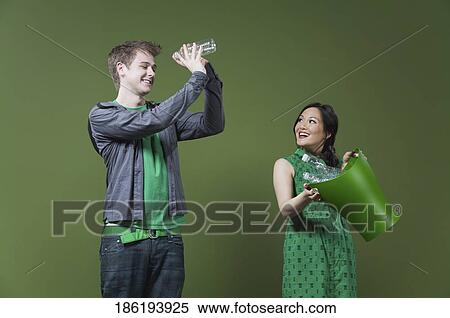 Woman holding a recycling bin and a man looking into an empty water bottle View Large Photo Image Stock Photography - Woman holding a recycling bin and a man looking into an empty water bottle. Fotosearch