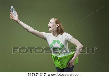 Woman holding a recycling bin and a plastic bottle View Large Photo Image Stock Photo - Woman holding a recycling bin and a plastic bottle. Fotosearch