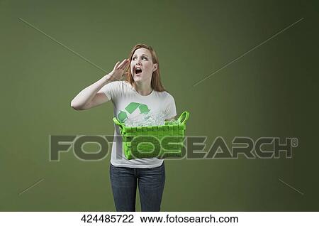 Stock Image - Woman holding a recycling bin and shouting. Fotosearch
