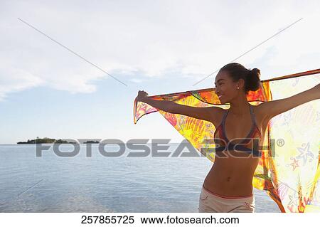 Woman holding a sarong on the beach View Large Photo Image Stock Photography - Woman holding a sarong on the beach. Fotosearch