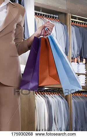 Woman holding shopping bags in a clothing store View Large Photo Image Stock Photo - Woman holding shopping bags in a clothing store. Fotosearch