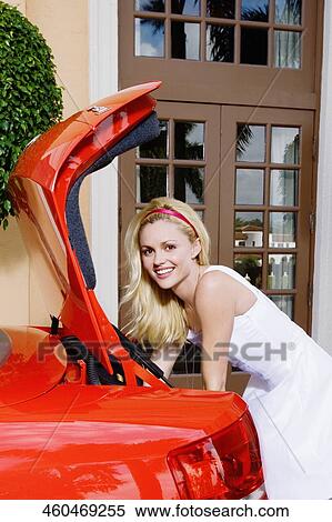 Stock Photography - Woman leaning against a car and smiling, Biltmore Hotel, Coral Gables, Florida, USA. Fotosearch