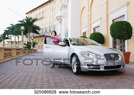 Stock Photo - Woman leaning against a car door and smiling, Biltmore Hotel, Coral Gables, Florida, USA. Fotosearch