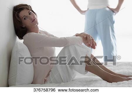 Stock Photograph - Woman looking sad with a man standing in the background. Fotosearch