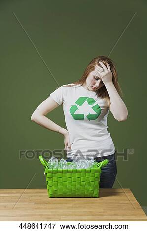 Woman looking tired and a recycling bin kept in front of her View Large Photo Image Stock Photo - Woman looking tired and a recycling bin kept in front of her. Fotosearch