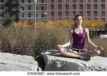 Stock Image - Woman meditating on a rock. Fotosearch