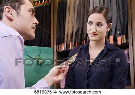 Woman paying by a credit card in a clothing store View Large Photo Image Picture - Woman paying by a credit card in a clothing store. Fotosearch