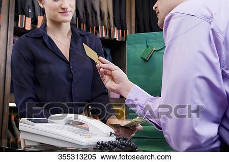 Woman paying by a credit card in a clothing store View Large Photo Image Stock Photography - Woman paying by a credit card in a clothing store. Fotosearch