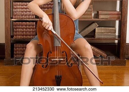 Woman playing a cello in a library View Large Photo Image Stock Image - Woman playing a cello in a library. Fotosearch
