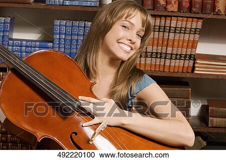 Woman playing a cello in a library View Large Photo Image Stock Image - Woman playing a cello in a library. Fotosearch