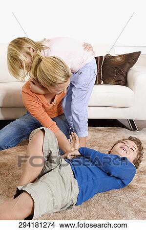 Picture - Woman playing with her son and a daughter in a living room. Fotosearch
